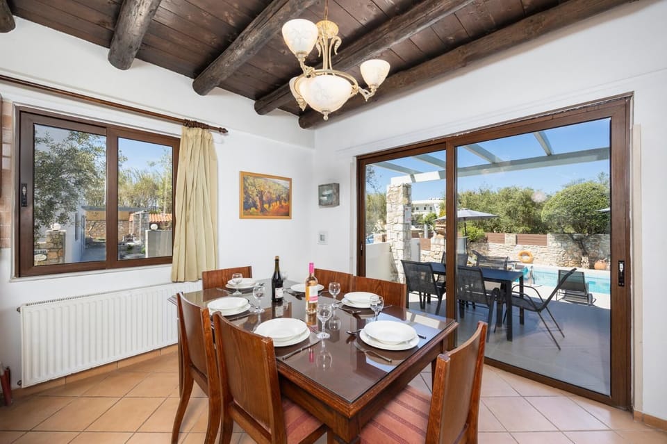 Open-plan living room with sofa, dining area, kitchen, indoor pool, ornamental fireplace, A/C, WiFi internet, and satellite TV