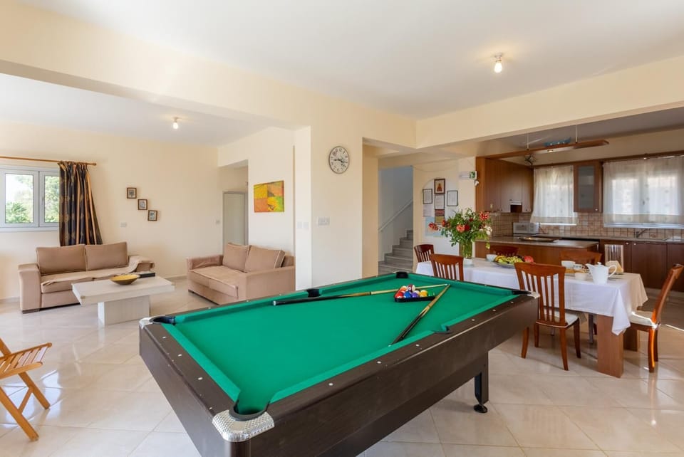 Open-plan living room with sofas, dining area, kitchen, ornamental fireplace, A/C, WiFi internet, satellite TV, pool table, foosball table, and terrace access with sea views