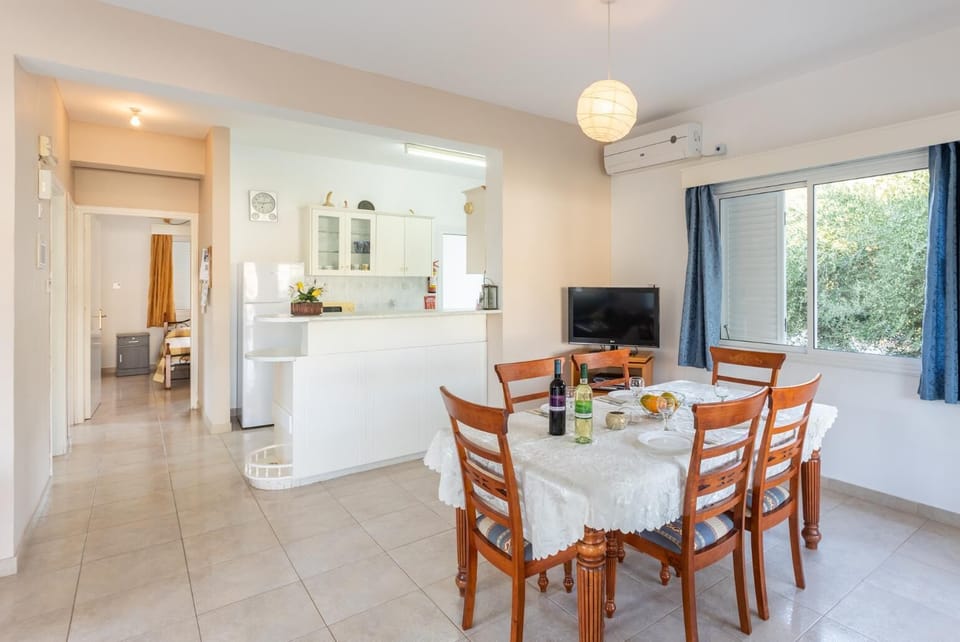 Open-plan living room with sofas, dining area, kitchen, A/C, WiFi internet, and satellite TV