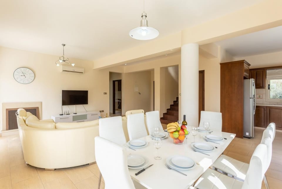 Open-plan living room with sofas, dining area, kitchen, ornamental fireplace, A/C, WiFi internet, and satellite TV