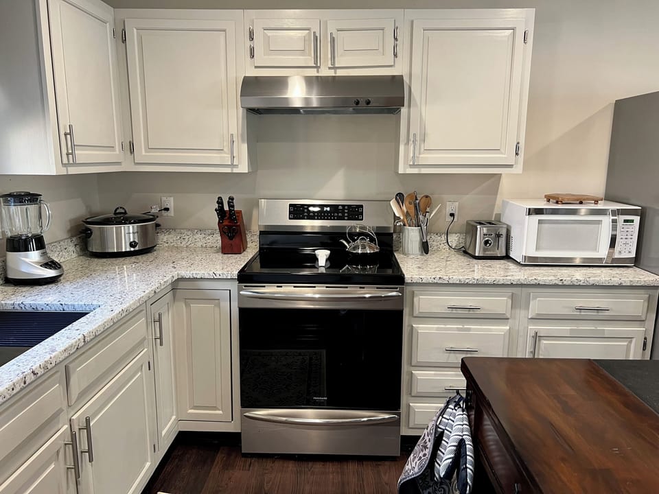 Fully equipped modern kitchen with induction range and stainless appliances.