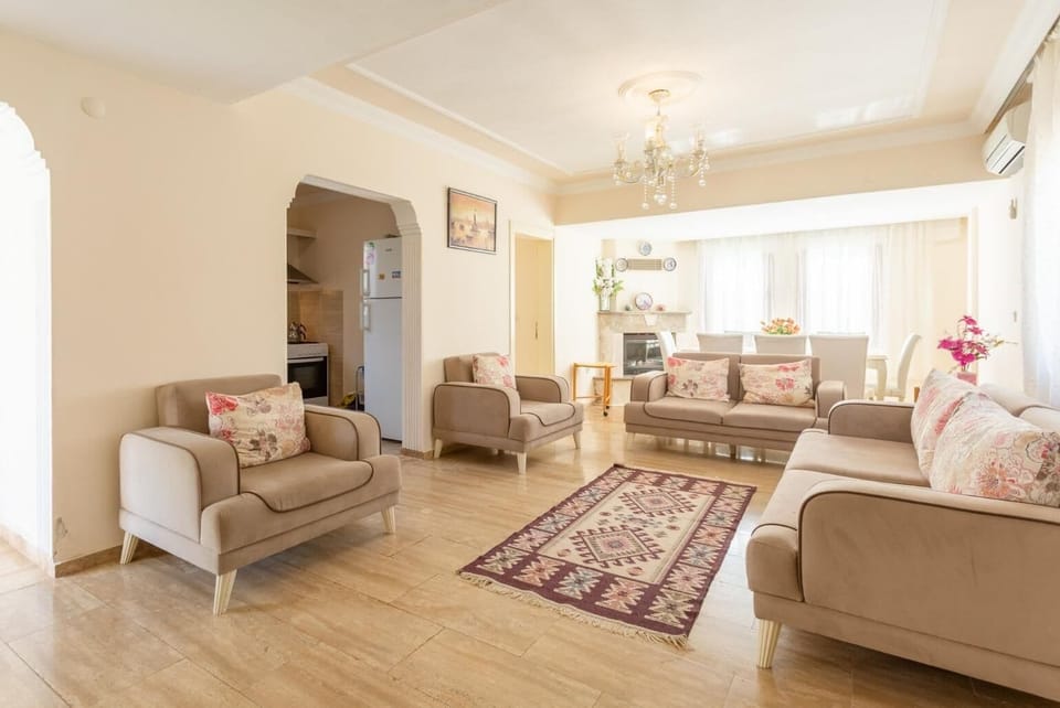 Open-plan living room with sofas, dining area, kitchen, ornamental fireplace, A/C, WiFi internet, satellite TV, and DVD player