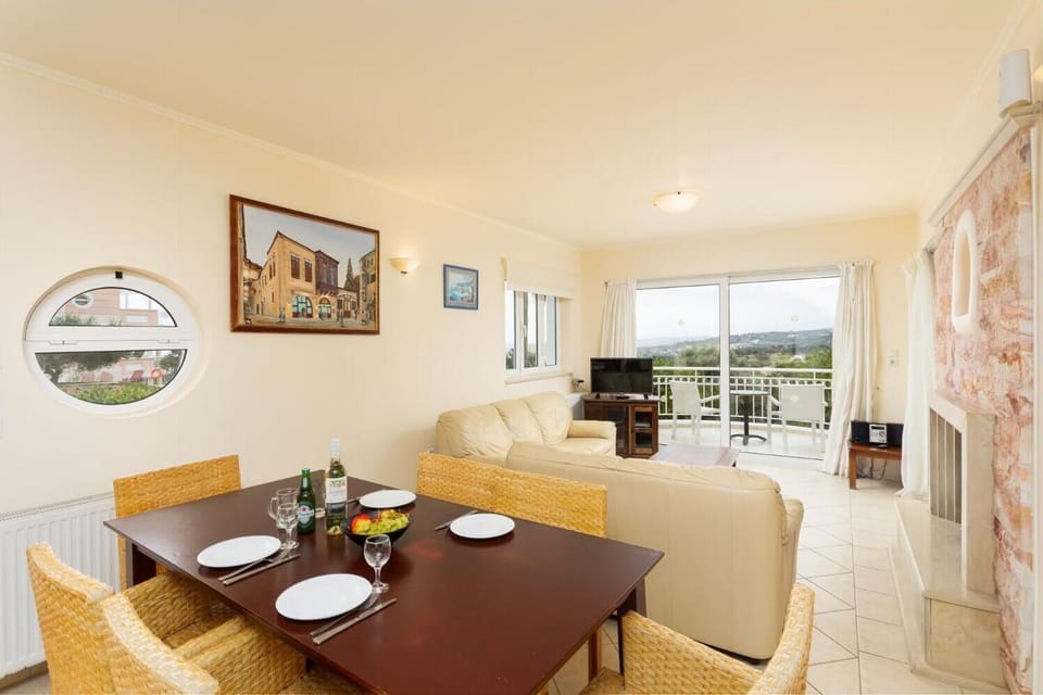 Open-plan living room with sofas, dining area, kitchen, ornamental fireplace, A/C, WiFi internet, and satellite TV