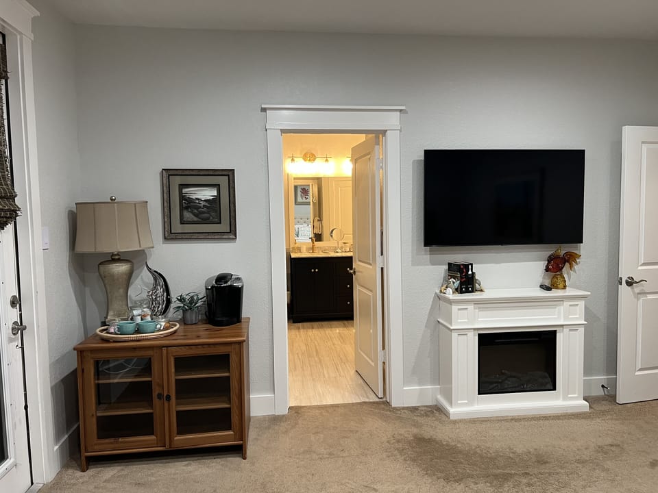 Cozy fireplace, smart TV & coffee bar in primary bedroom.