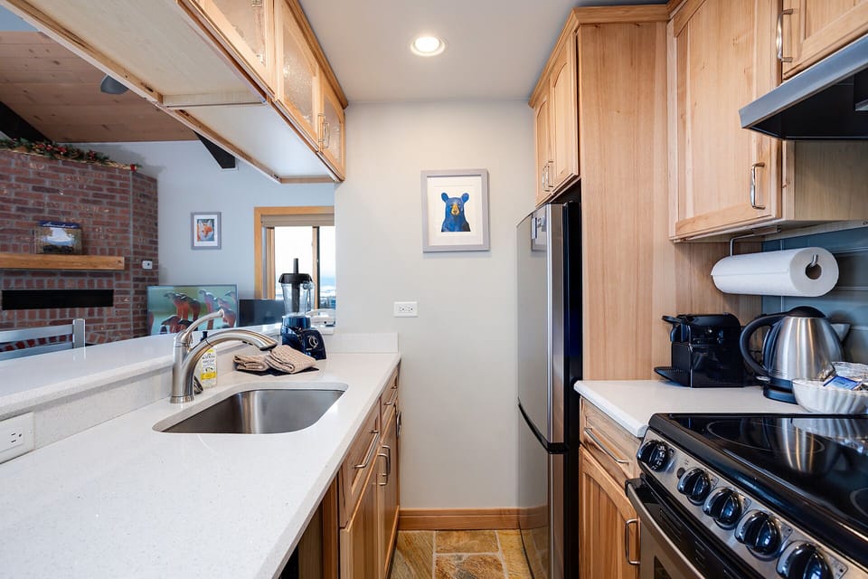 Cook your favorite meals in this fully-equipped galley kitchen featuring warm wood cabinets, modern appliances, and everything you need for a comfortable stay.