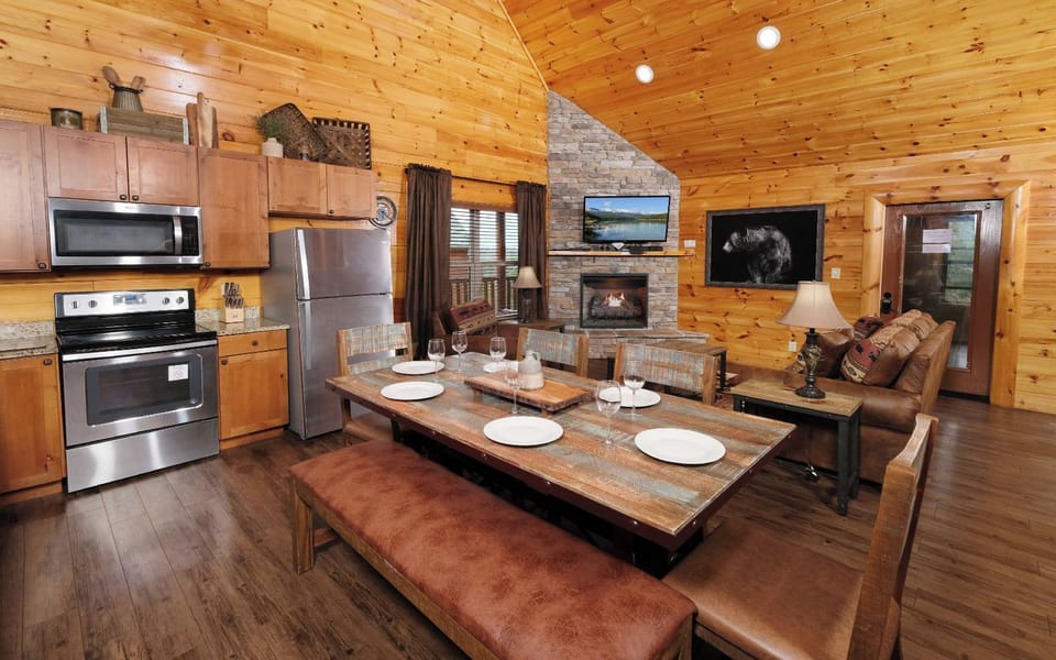 Rustic dining area beside the fully equipped kitchen and stone fireplace.