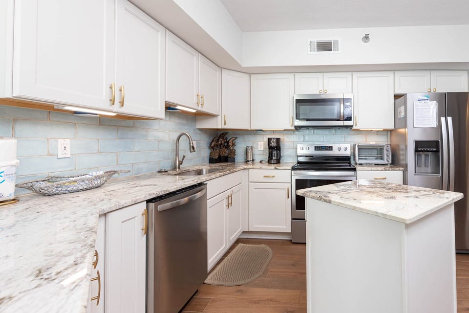 The kitchen features stainless appliances, granite countertops, and a charming blue tile backsplash for a refreshing look