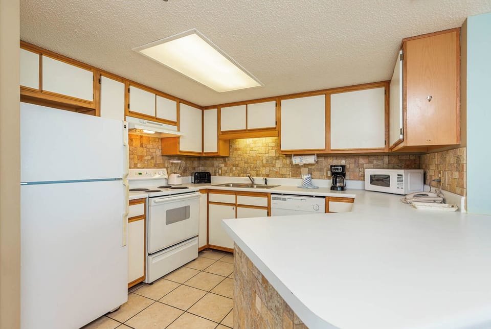Bright kitchen features white cabinetry, a spacious countertop, and a cozy breakfast bar perfect for casual dining