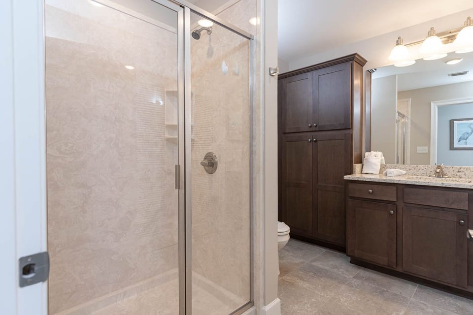 Enjoy a relaxing shower after a day at the beach in this guest bath with stylish cabinetry and spacious vanity