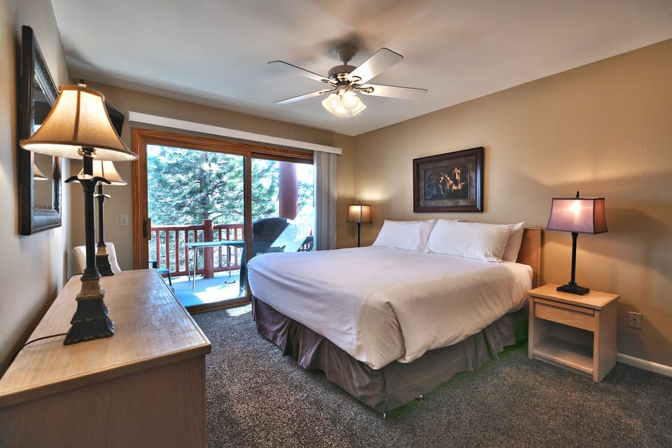 Main bedroom features a king-sized bed with white linen and a ceiling fan with light fixture