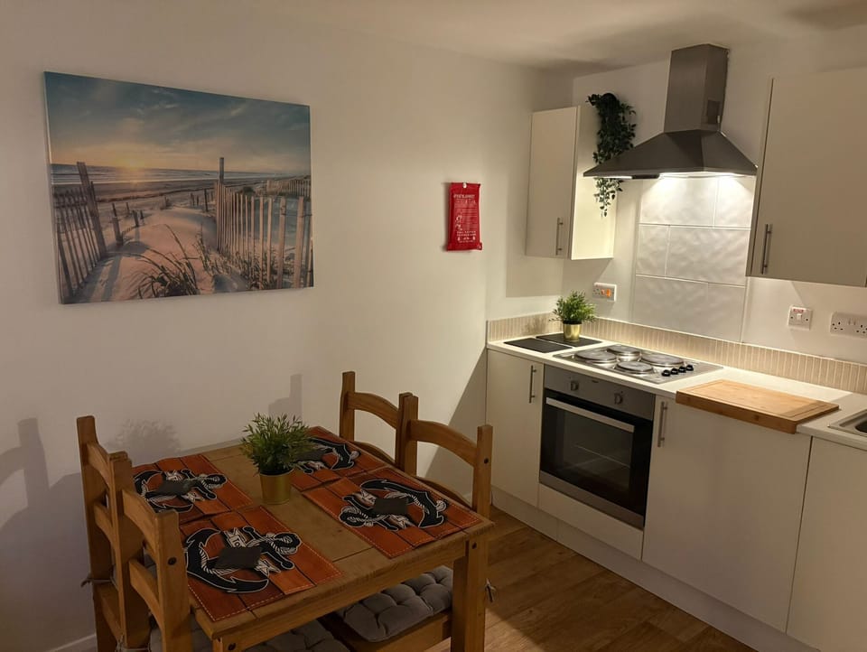 Modern open-plan kitchen and dining area with wooden chairs and wall art, fully equipped for self-catering stays – Castle 10 - Southampton
