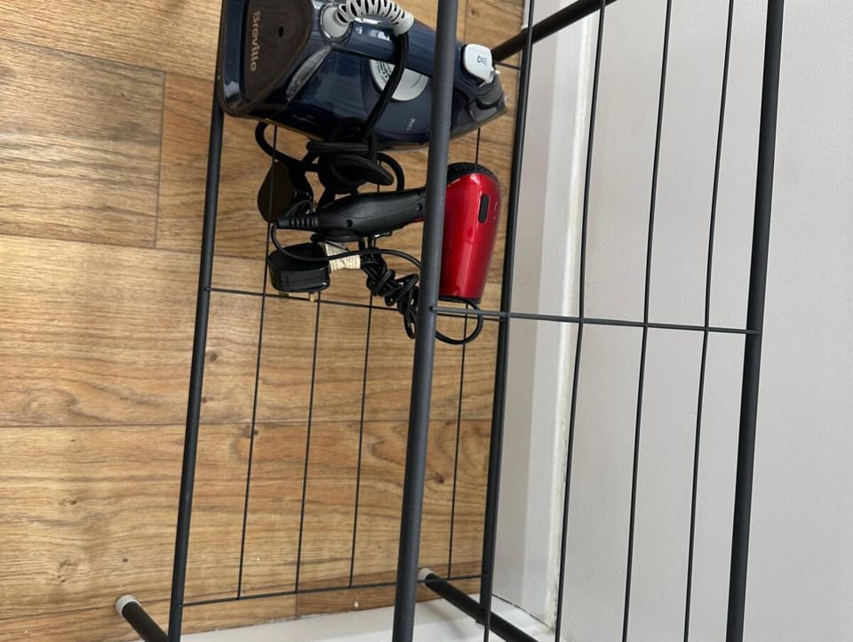 Storage area with wardrobe, black metal rail, and ironing board in serviced apartment – Castle 10 - Southampton