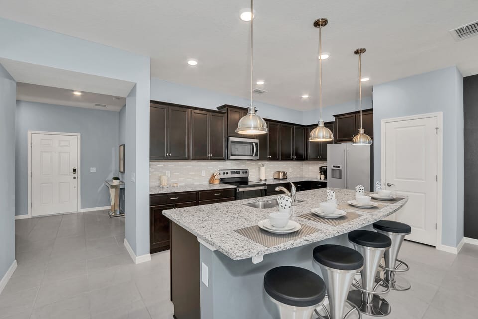 The kitchen with its inviting bar table beckons for lively conversations and casual meals, creating a cozy space where memories are shared and laughter echoes.