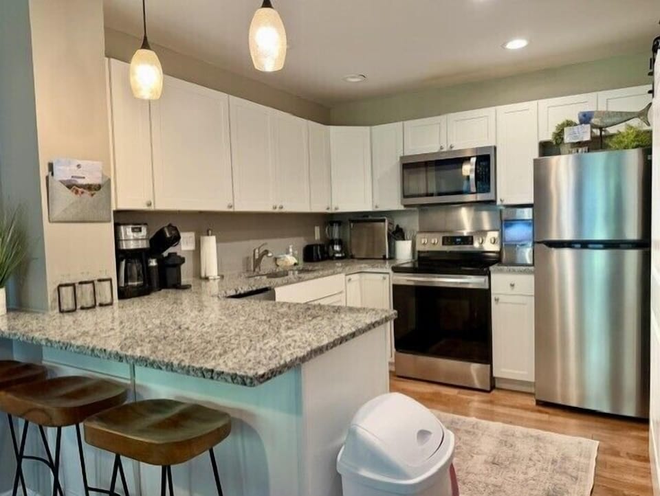 Kitchen with barstools, hanging bar lights, and plenty of space for cooking meals.