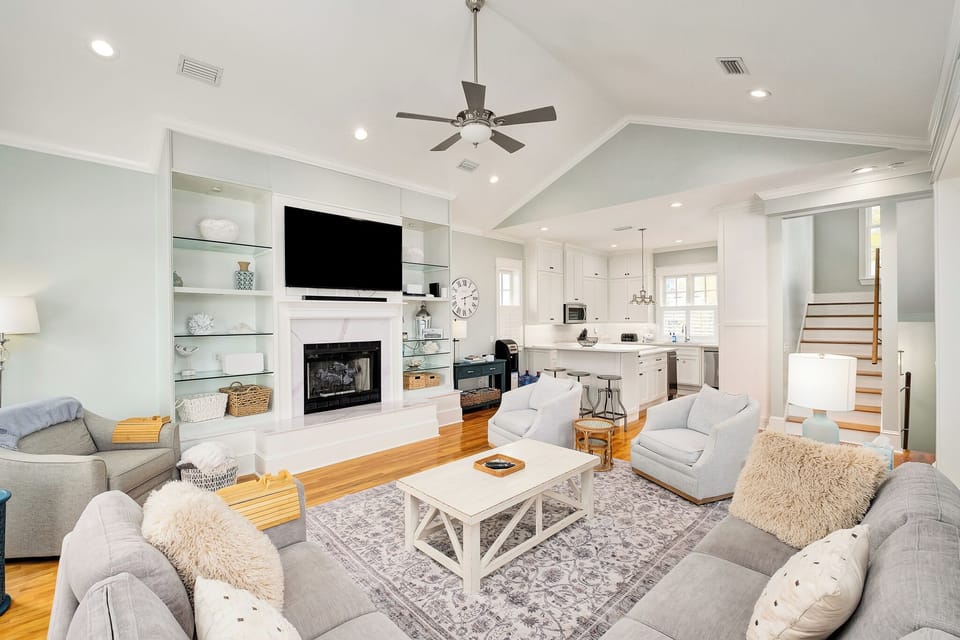 Unwind in your elegant open-plan living space, where plush seating surrounds a cozy fireplace and gleaming hardwood floors invite barefoot comfort.