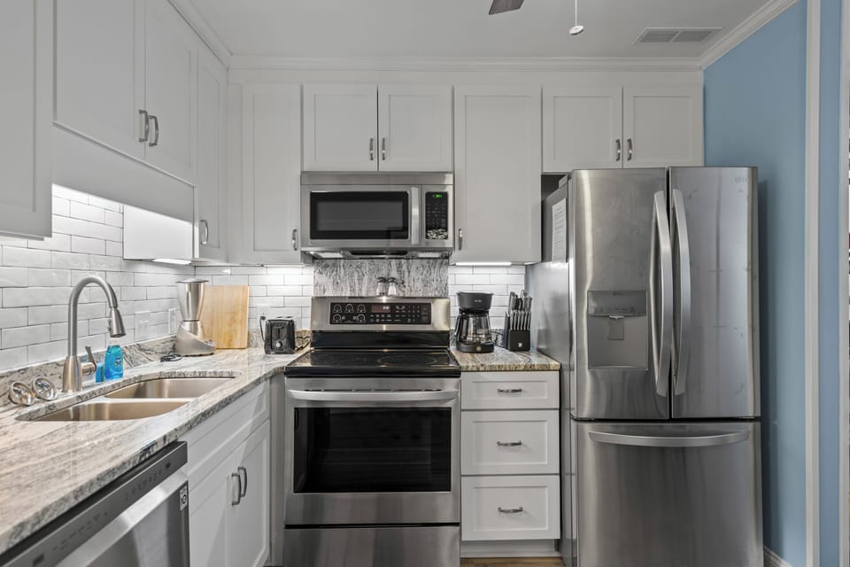 Cook your favorite meals in this bright, fully-equipped kitchen featuring stainless steel appliances and elegant granite countertops.
