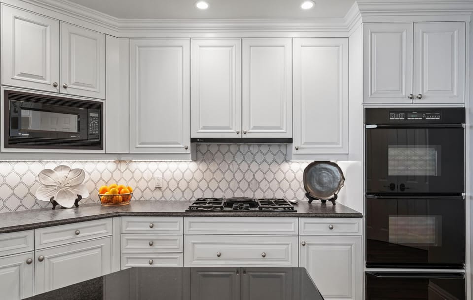 Black double ovens and a built-in microwave contrast with white cabinetry in the kitchen.