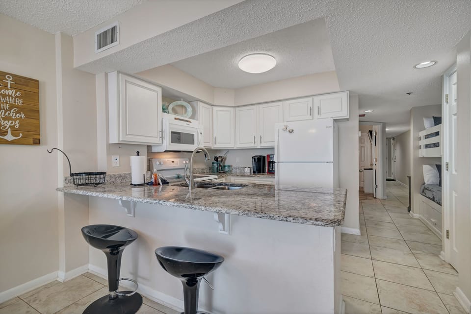 This beautifully designed kitchen boasts a spacious island with a contrasting stone countertop and stylish stools, creating a natural hub within the home.