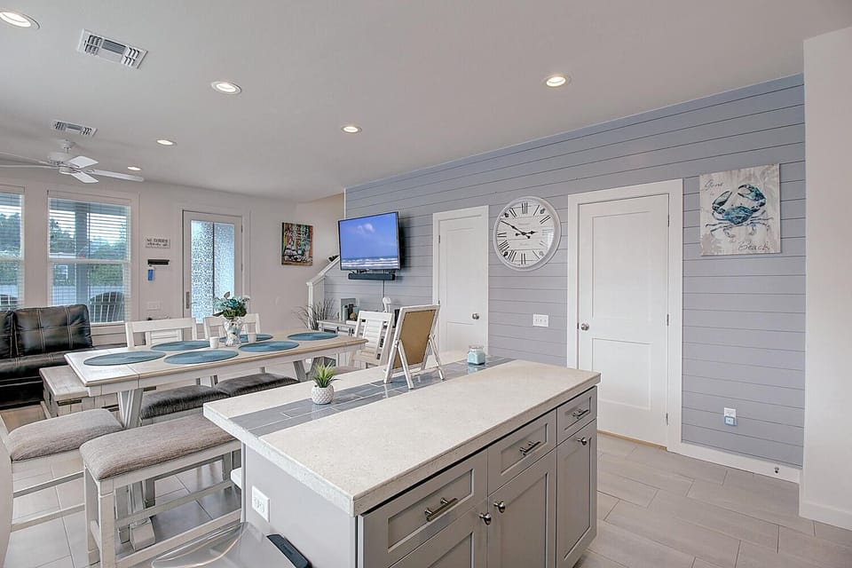 Your open-concept kitchen flows seamlessly into the dining area, where coastal decor and modern amenities create the perfect gathering space for meals.