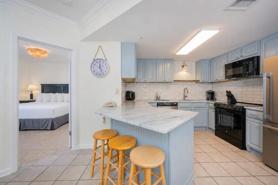 Bright kitchen with soft blue cabinets invites you to prepare meals while chatting with family nearby in the master suite