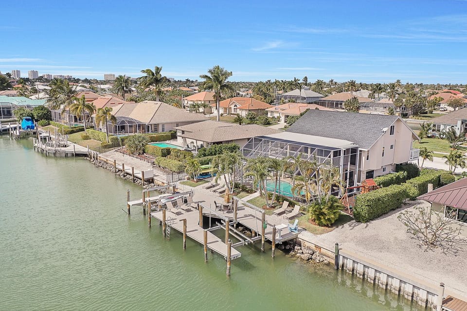Aerial view of waterway, expansive dock   area w/ 8 lounge chairs, 4 seat table