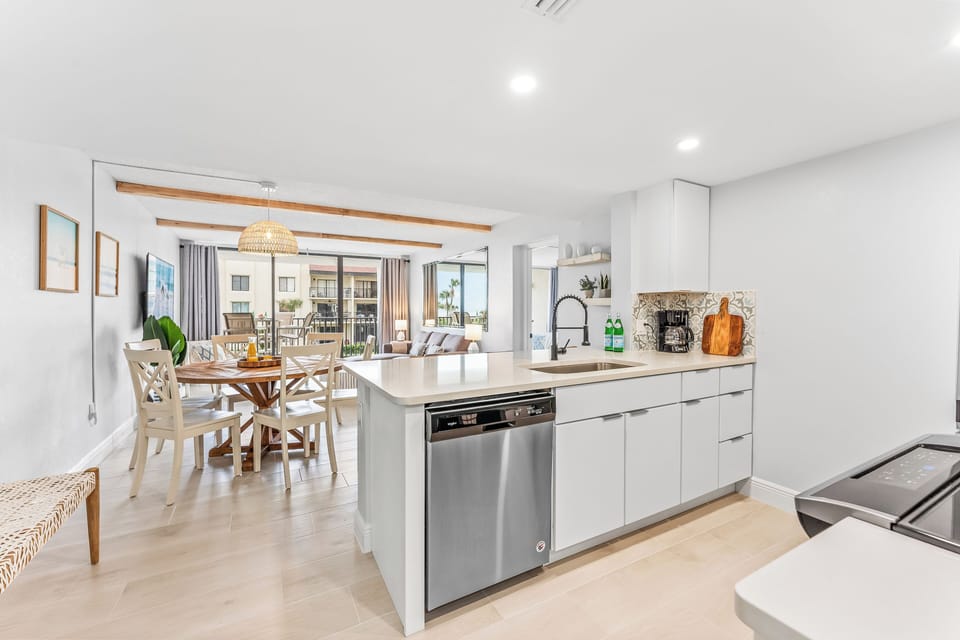 Modern kitchen with sleek stainless steel appliances, an open layout, and a view of the dining area.