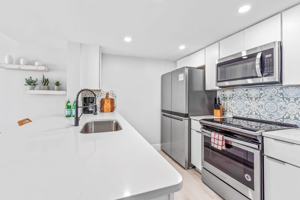 Modern kitchen with white cabinetry, stainless steel appliances, and a sleek backsplash.