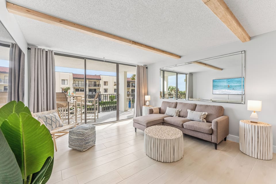 Spacious living room with warm tones, stylish furniture, and a view of the balcony.