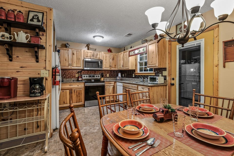 Fully equipped kitchen with stainless steel appliances and adjacent dining area seating four at Amazing Dreams cabin in Sevierville, Tennessee — just minutes from Pigeon Forge.