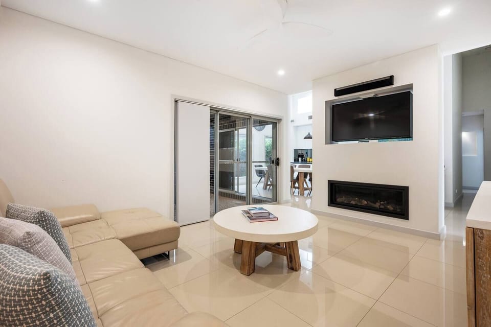 The cosy living area has a family-style L-shaped sofa, smart TV and a sleek fireplace.
