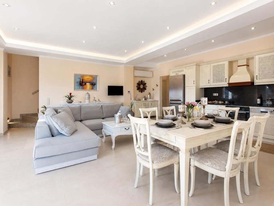 Open-plan living room with sofas, dining area, kitchen, A/C, WiFi internet, satellite TV, DVD player, and terrace access with sea views