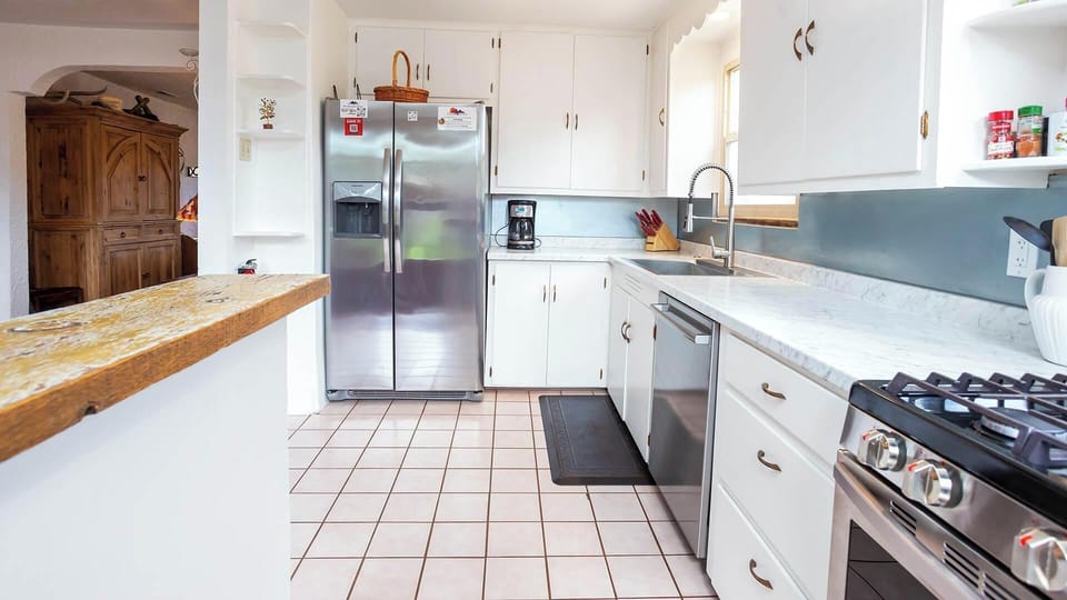 Fully equipped kitchen with stainless steel appliances and white cabinets at this historic Kanab adobe rental.
