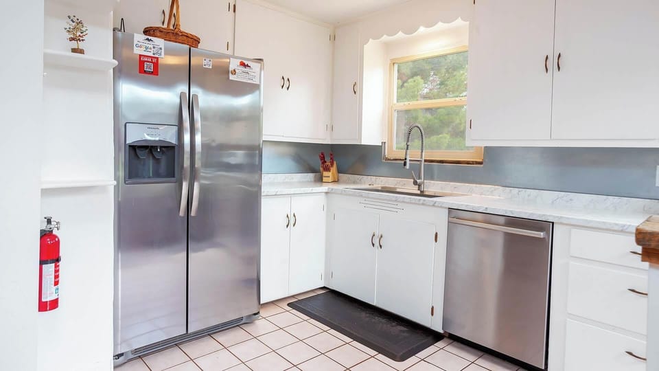 Bright white kitchen with stainless steel appliances and tile floors at this historic Kanab vacation rental.