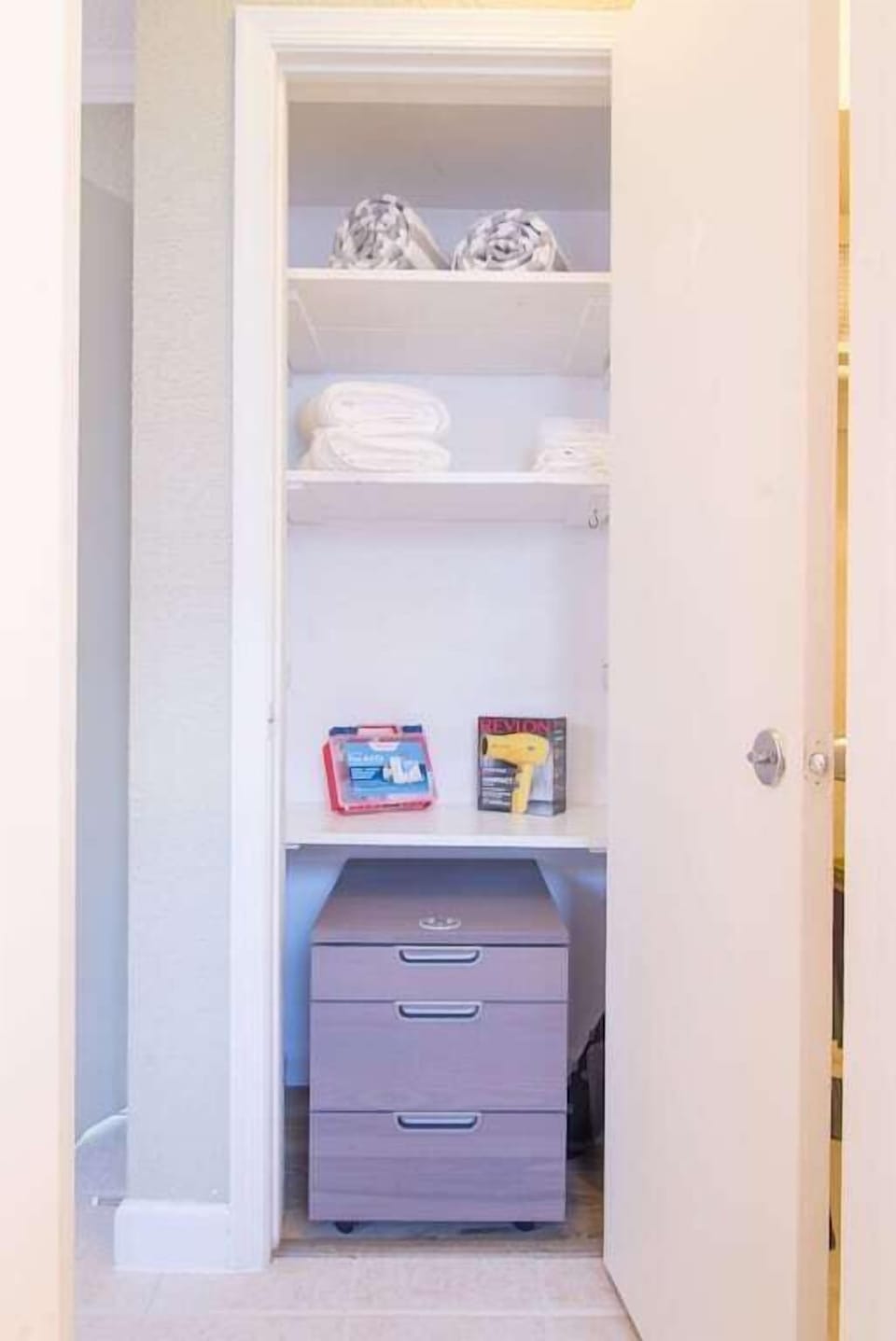 Linen closet includes fluffy bath towels, beach towels, a hair dryer and first aid kit.