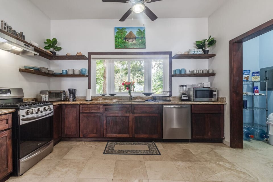 The kitchen combines function and charm with open upper shelves and a sea-inspired atmosphere. Equipped with a gas stove, toaster oven, coffee maker, microwave, blender, and more, it has everything a cook needs to create delicious meals.