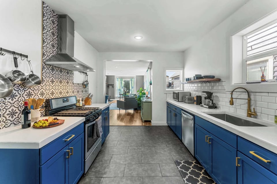 A modern kitchen with quartz counters, blue cabinets, and stainless appliances.