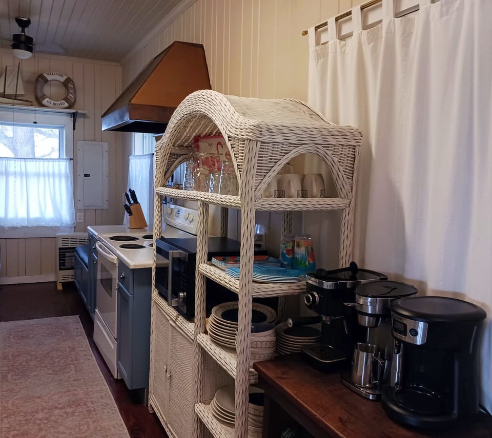 Kitchen with range, microwave, coffee station, and plenty of dishes.