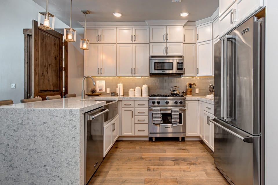 Fully Equipped Gourmet Kitchen with opulent stone countertops, stainless steel Viking appliances, and bar seating for four