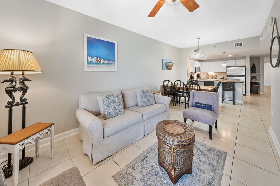 Relax in your spacious living area with comfortable seating, coastal artwork, and an open layout flowing seamlessly into your fully equipped kitchen.