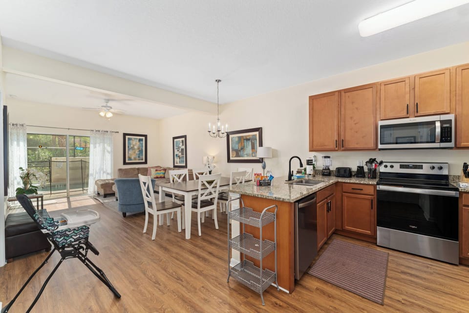 Welcome to a stunning kitchen featuring warm wooden cabinetry and modern stainless-steel appliances, seamlessly connected to a cozy dining area, all bathed in natural light from large windows for an inviting atmosphere.