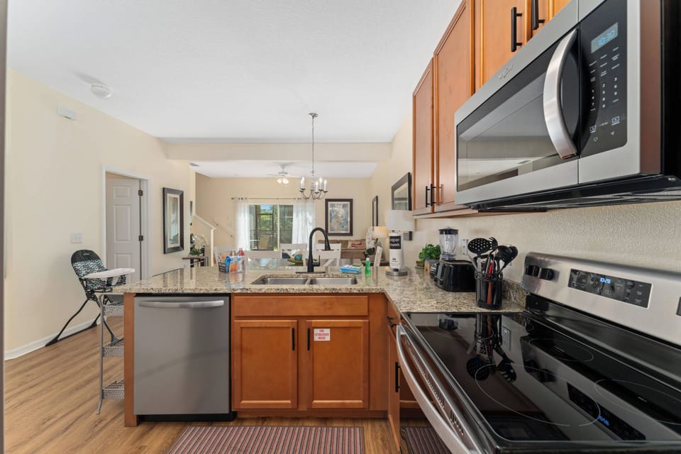 Welcome to a beautiful kitchen with rich wooden cabinets and sleek stainless steel appliances, all illuminated by natural light that highlights the granite countertops, inviting you to create culinary delights in style and.