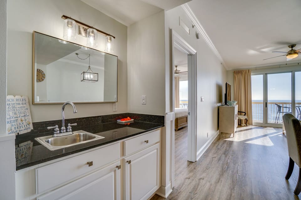 Your bright kitchen flows seamlessly into the open living space, where ocean views through floor-to-ceiling windows create the perfect backdrop for morning coffee.