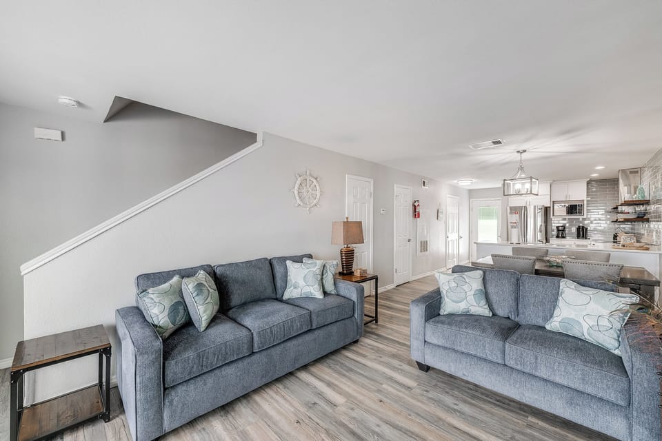 Sink into plush blue sofas where you'll unwind after your adventures, enjoying the open flow to your fully equipped kitchen.