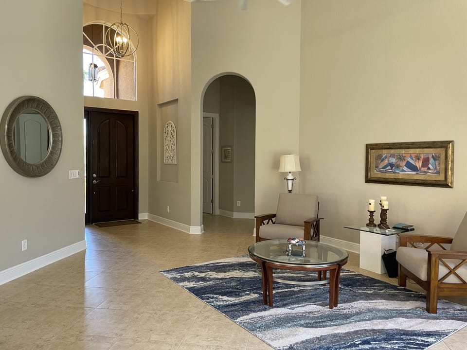 Entry area with beautiful large wooden front door and modern chandelier above. 