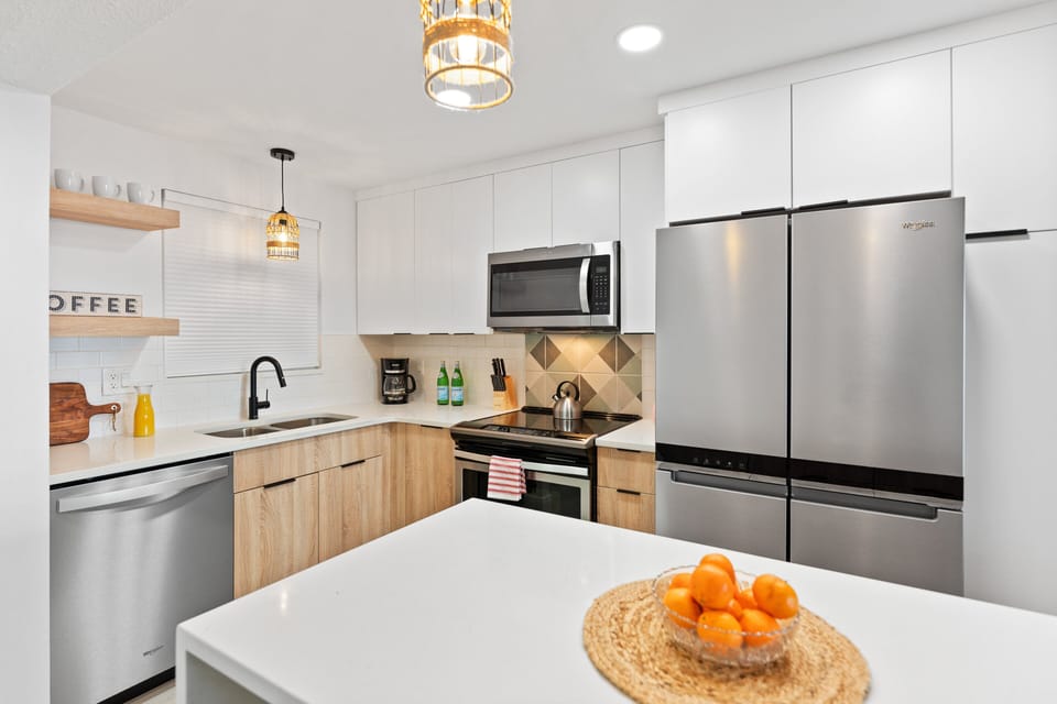 Fully equipped kitchen with modern white cabinetry, wood accents, and a coffee station for a perfect morning start.