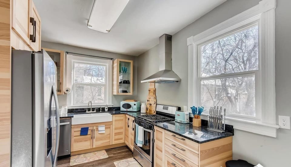- Sleek kitchen with two tone cabinets, granite counters, and a deep farmhouse sink
- Stainless appliances and open shelving make cooking easy and stylish
- Large windows keep the space bright and inviting all day