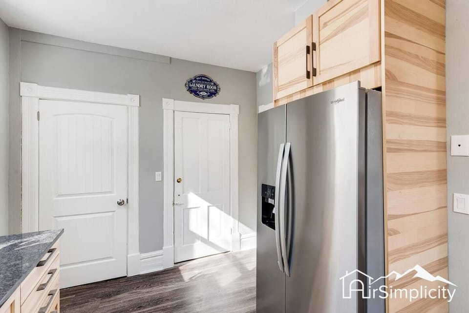 - Sleek stainless steel fridge with upper cabinets for extra storage and organization
- Back door provides easy access for unloading groceries or stepping out
- Wood floors and farmhouse style trim tie the space together beautifully

