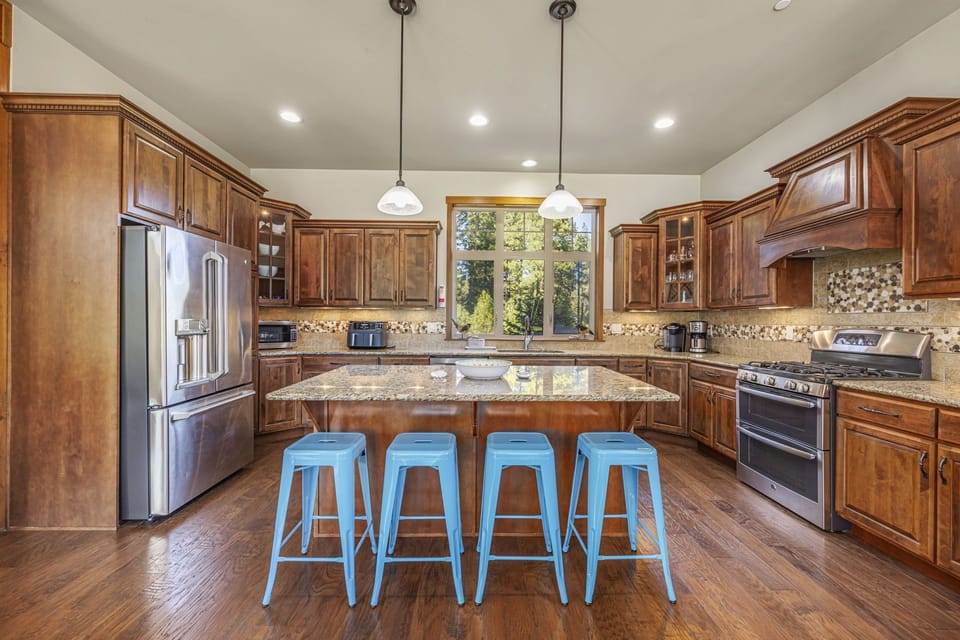 Custom kitchen with rich natural wood, granite counters, and casual island seating