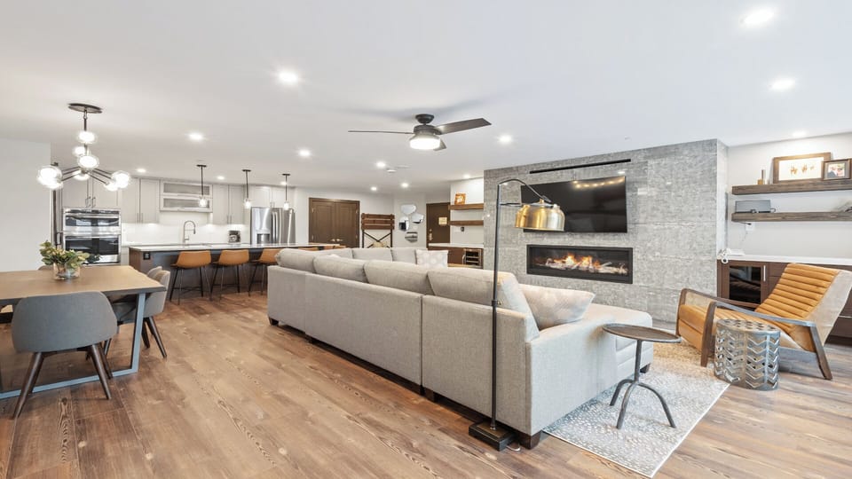 You'll love gathering in this stunning open-concept space, where modern comfort meets thoughtful design. Rich hardwood floors flow seamlessly beneath soaring ceilings, while the fireplace creates a cozy ambiance for memorable evenings together.