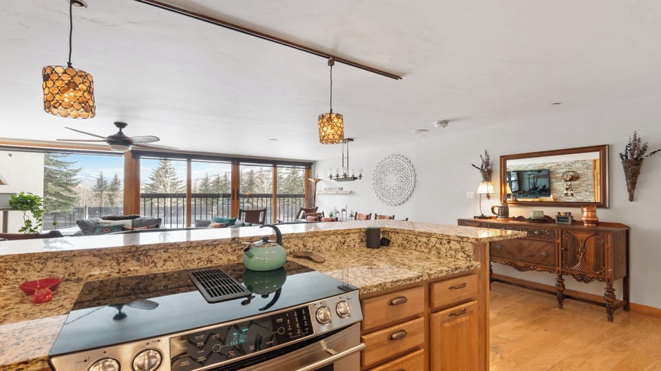 Cook in a sun-filled kitchen with granite counters and watch the trees sway through expansive windows. The open layout lets you chat with guests while you prep meals in this warm, inviting space.